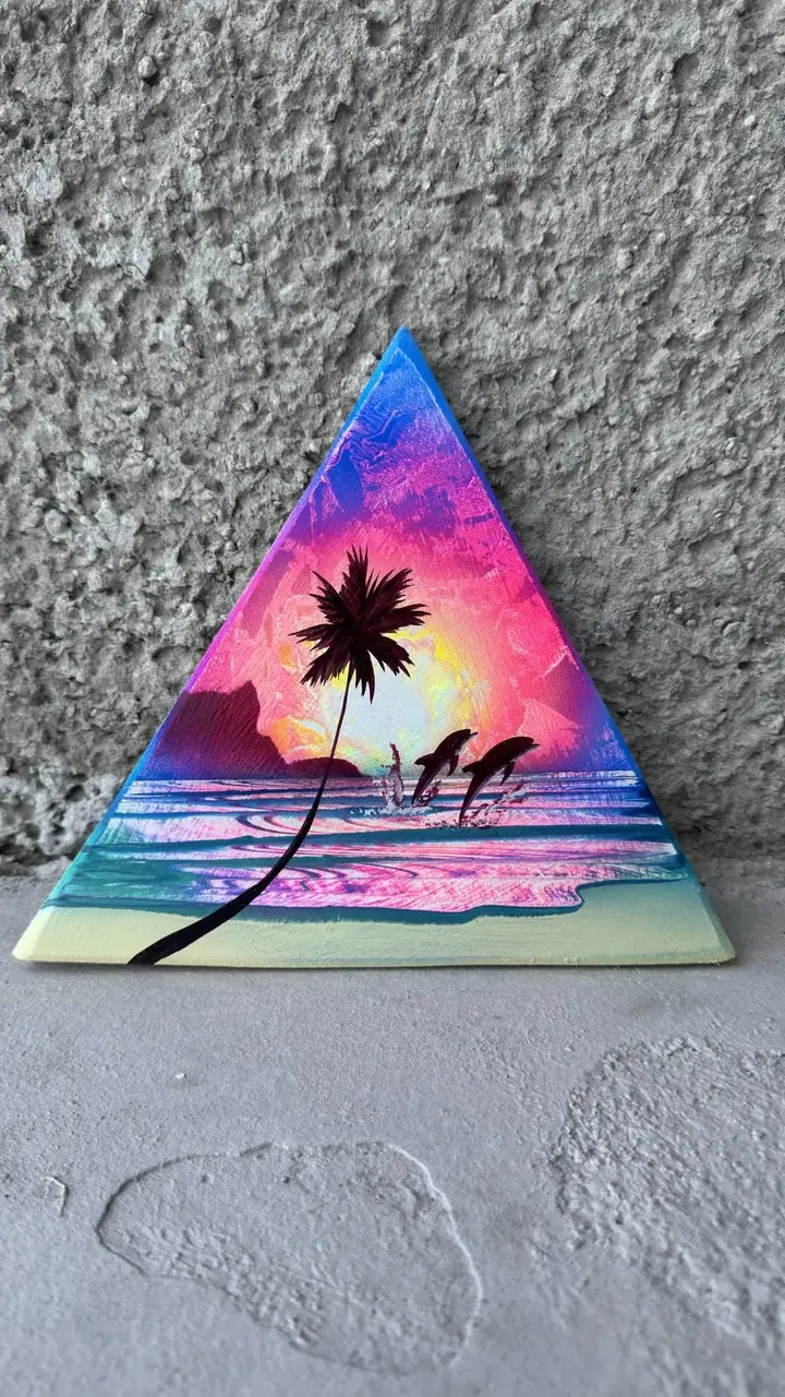 Triangle painting of a pink and blue sunset over the sea with a palm tree and two dolphins