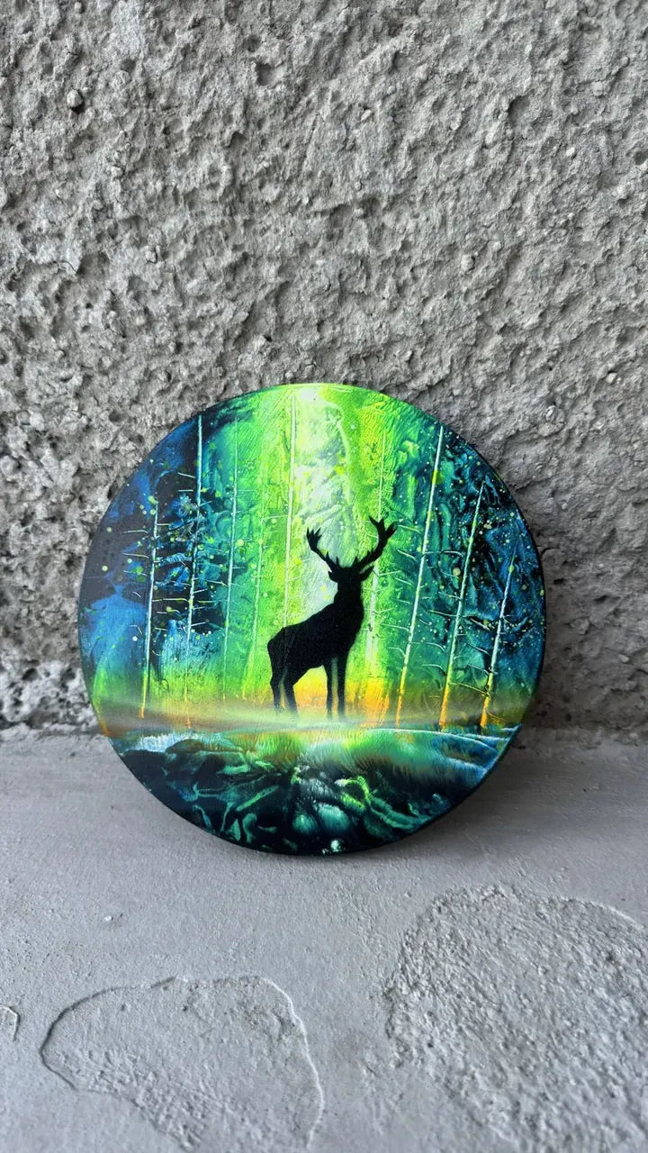 Circle painting of a stag silhouetted in a glowing green forest