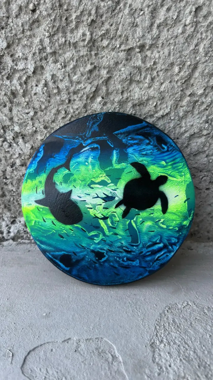 Circle painting of a sea turtle and a shark in bright green and blue water